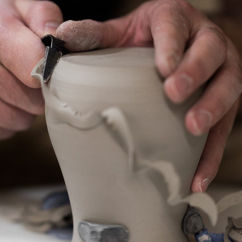 person holding white ceramic vase